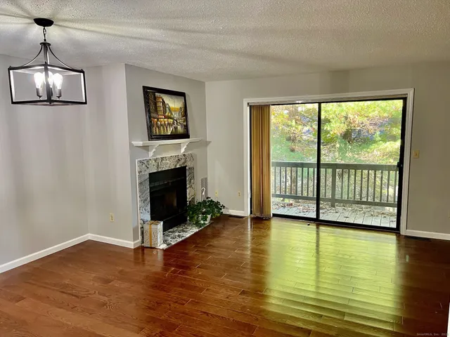 a view of a livingroom with wooden floor a fireplace and window