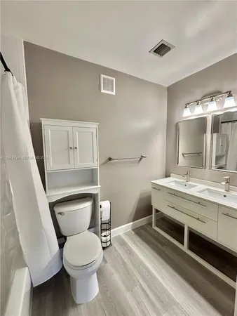 a bathroom with a granite countertop toilet a sink and a mirror