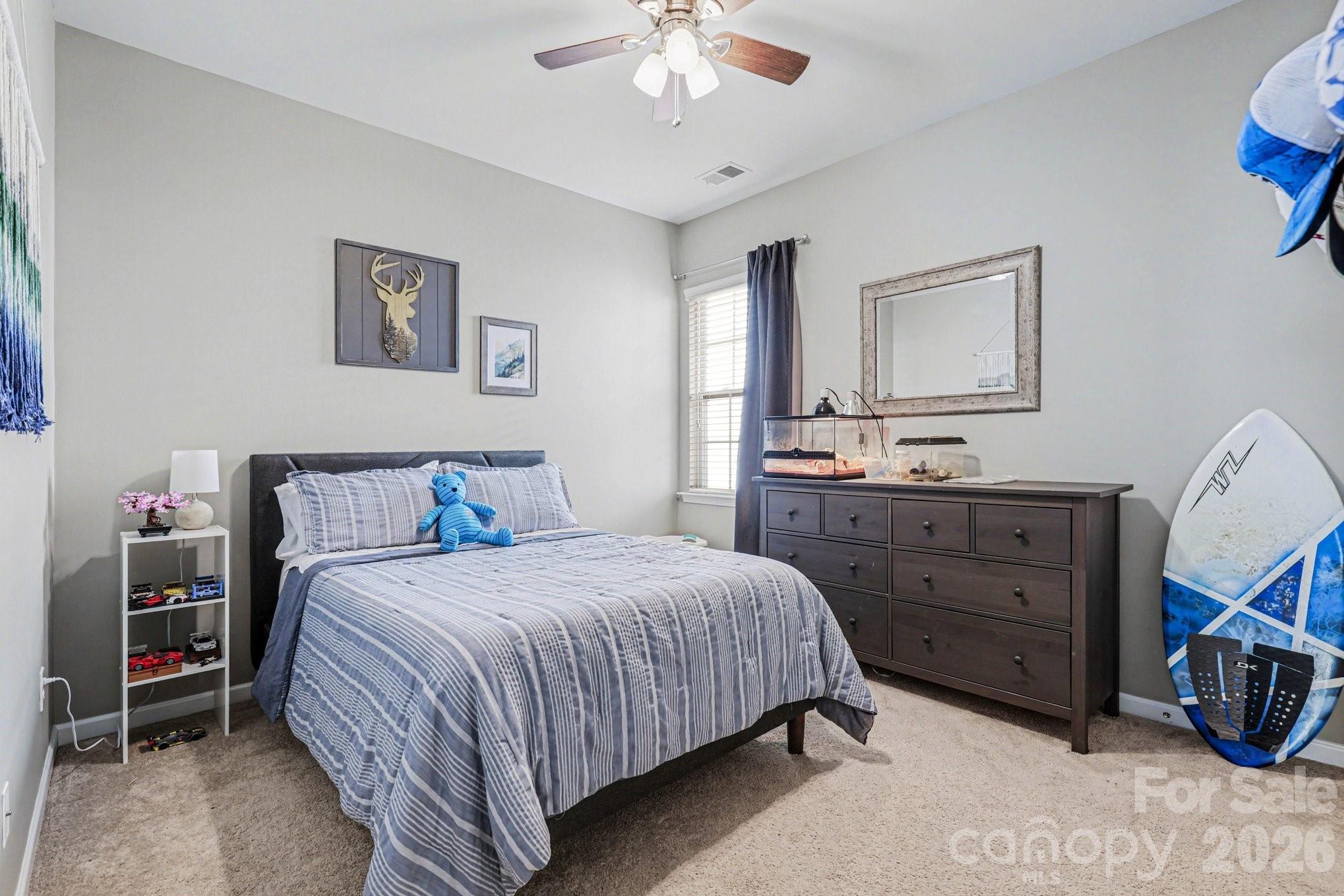 5153 Waterloo Drive Tega Cay, SC 29708 - Photo 18 of 29 a bedroom with a bed a chandelier and a dresser