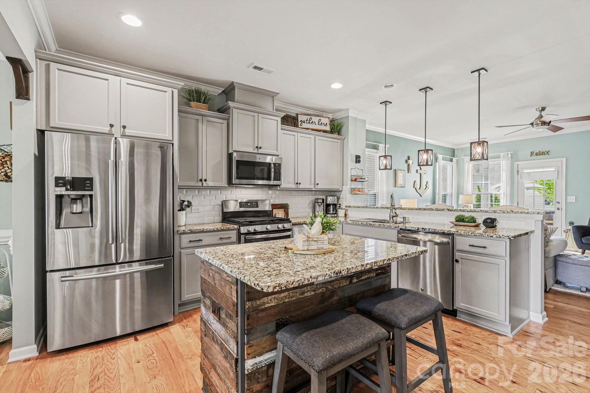 5153 Waterloo Drive Tega Cay, SC 29708 - Photo 8 of 29 a kitchen with kitchen island granite countertop a refrigerator a stove a sink and white cabinets with wooden floors
