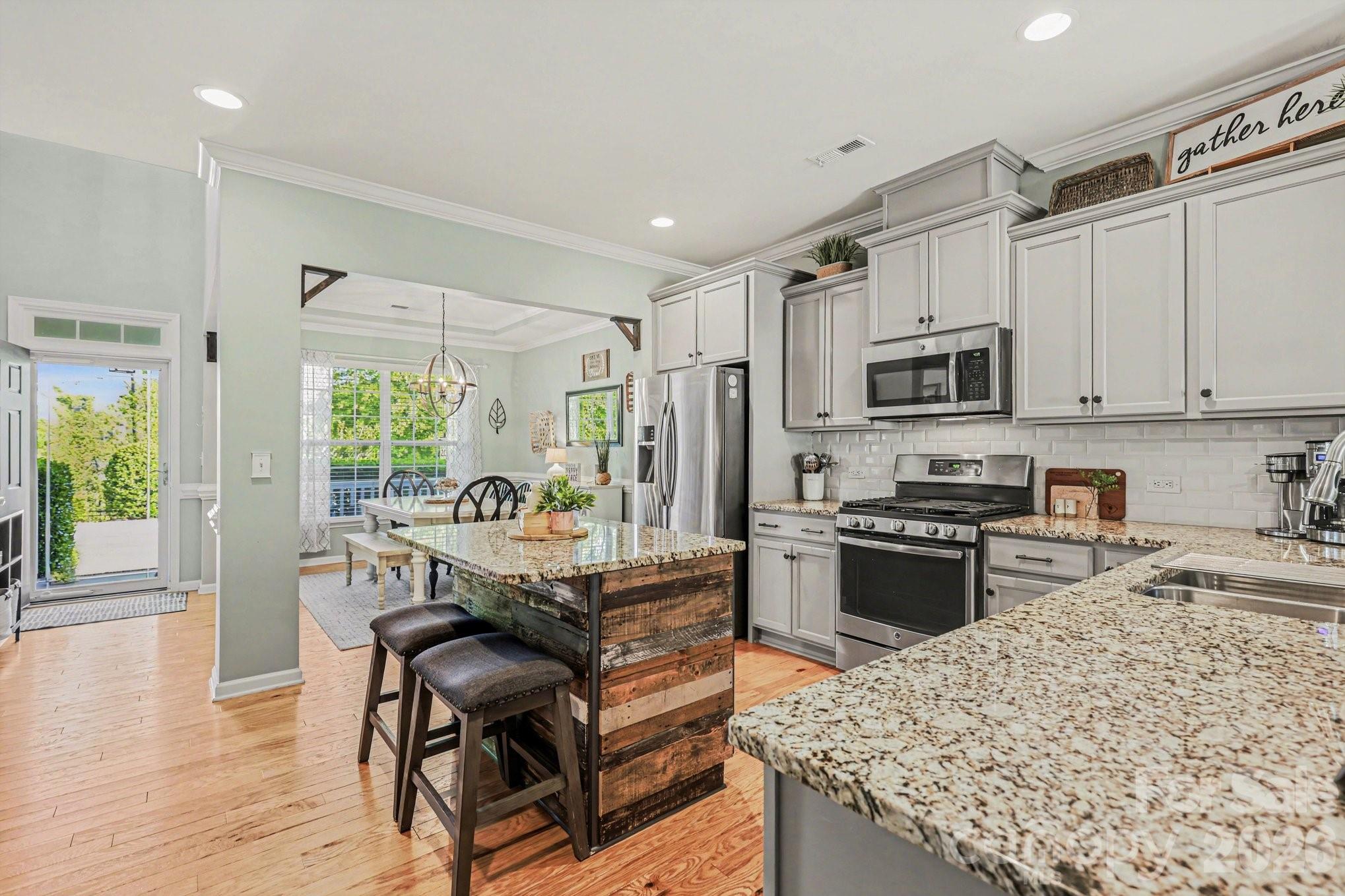 5153 Waterloo Drive Tega Cay, SC 29708 - Photo 9 of 29 a kitchen with kitchen island granite countertop a stove top oven a sink a dining table and chairs