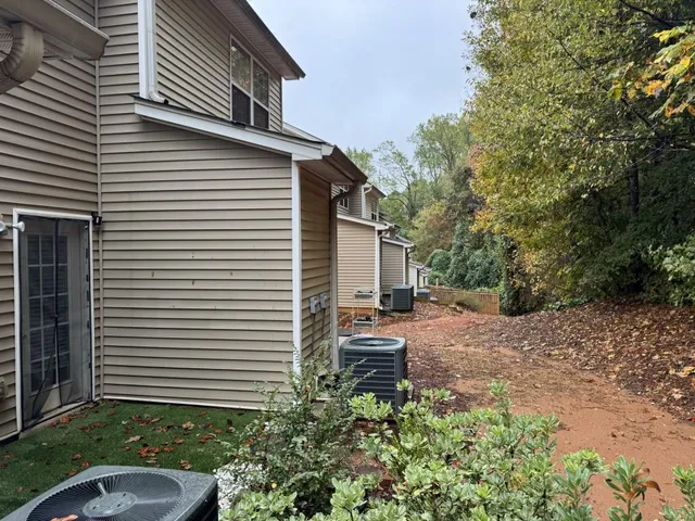 a backyard of a house with plants and barbeque oven