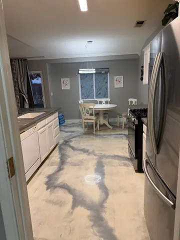 a living room with stainless steel appliances furniture a refrigerator and a window