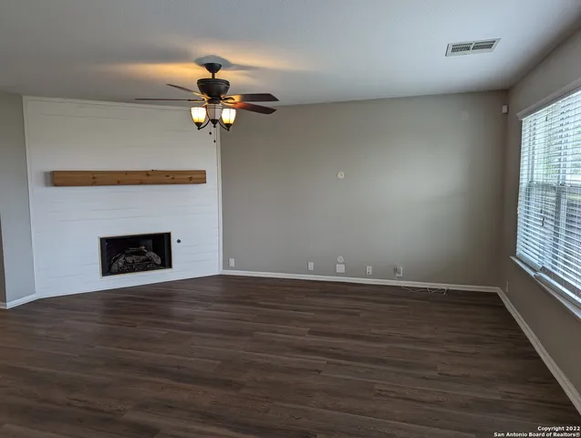 a view of a livingroom with a fireplace a ceiling fan and wooden floor