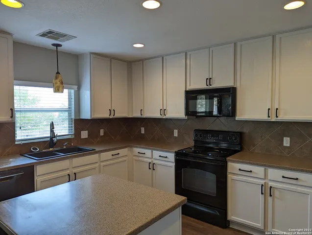 a kitchen with granite countertop a sink a stove and cabinets