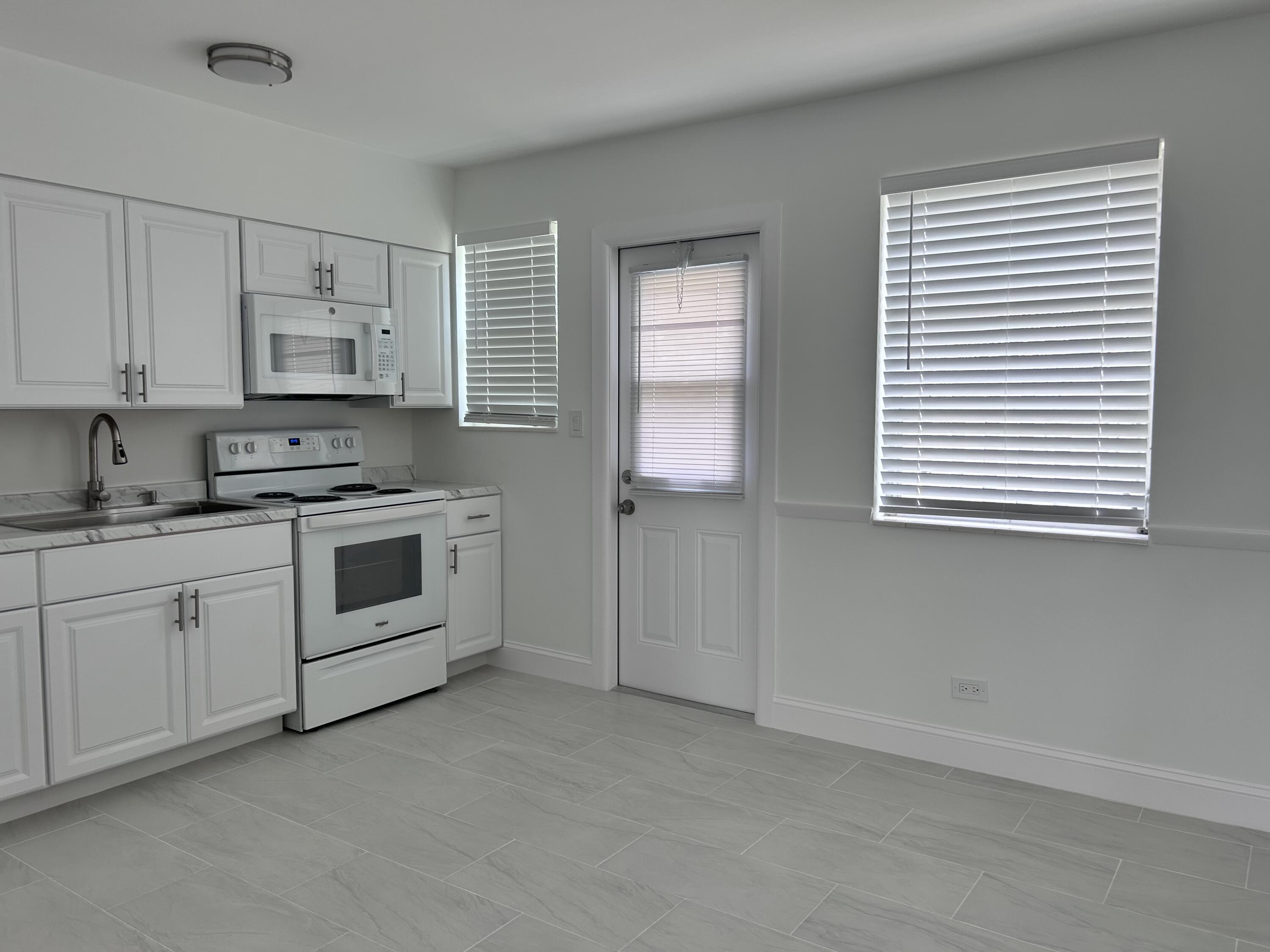 630 Prosperity Farms Road, Unit 2 North Palm Beach, FL 33408 - Photo 5 of 13 a kitchen with cabinets appliances and a window