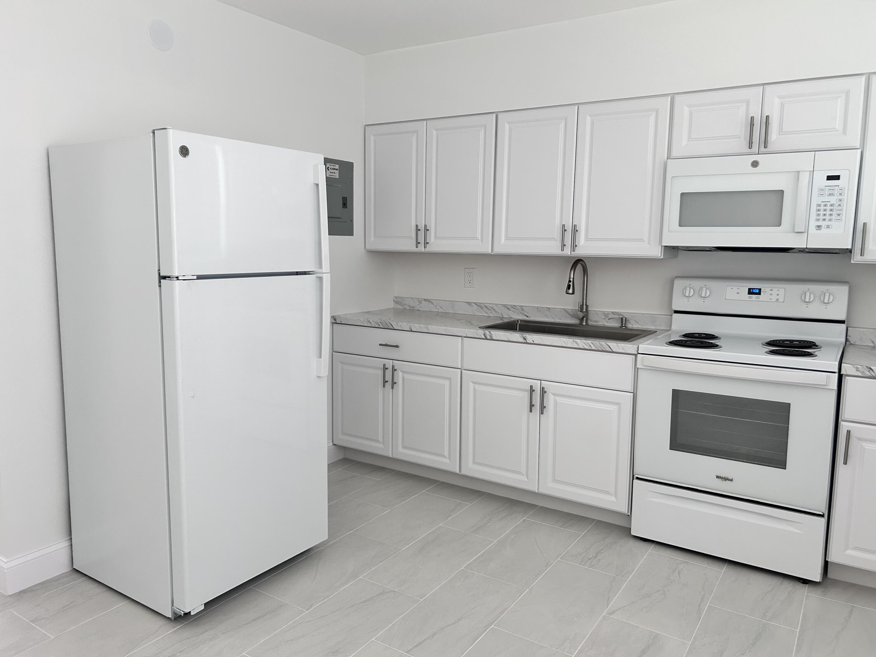 630 Prosperity Farms Road, Unit 2 North Palm Beach, FL 33408 - Photo 6 of 13 a kitchen with white cabinets and white appliances