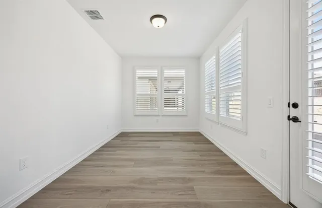 an empty room with wooden floor and windows