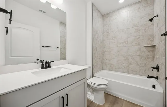 a bathroom with a bathtub shower sink vanity mirror and toilet