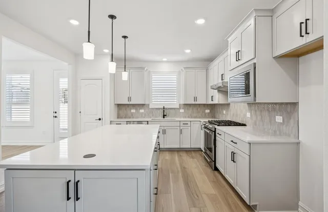 a kitchen with a sink a stove a refrigerator and white cabinets