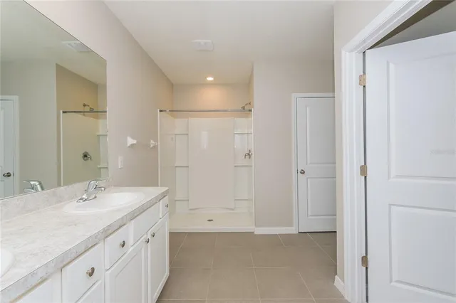 a spacious bathroom with a shower sink and mirror