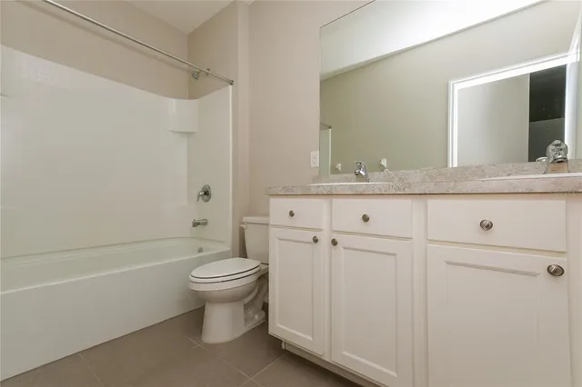a bathroom with a granite countertop toilet a sink and a mirror