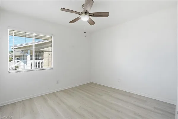 an empty room with a window and a fan