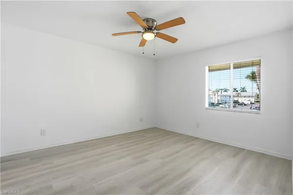 an empty room with ceiling fan and window