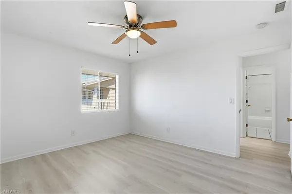 an empty room with a window and a fan