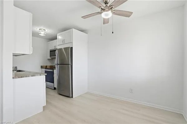 an empty room with kitchen and a refrigerator