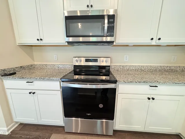 a kitchen with stainless steel appliances granite countertop white cabinets and a stove a sink