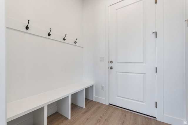 58 South Crimson Way, Unit 306 Mapleton, UT 84664 - Photo 13 of 24 Entryway featuring a built-in bench with cubby storage, wall-mounted coat hooks, a paneled door with brushed nickel hardware, and wood-finish flooring