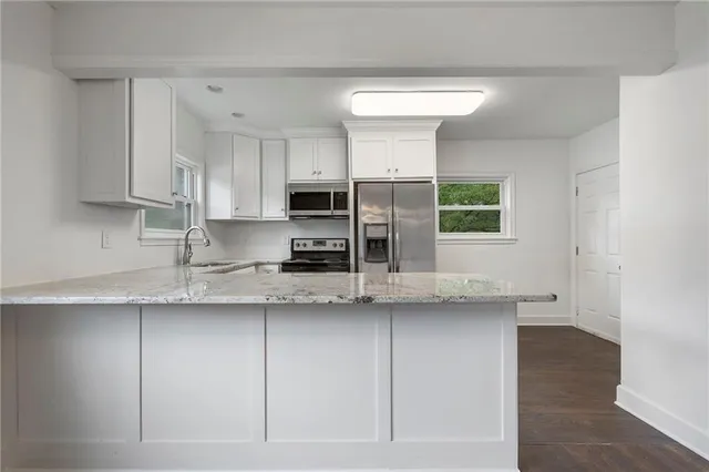 a kitchen with stainless steel appliances granite countertop a sink a stove a microwave a refrigerator and cabinets