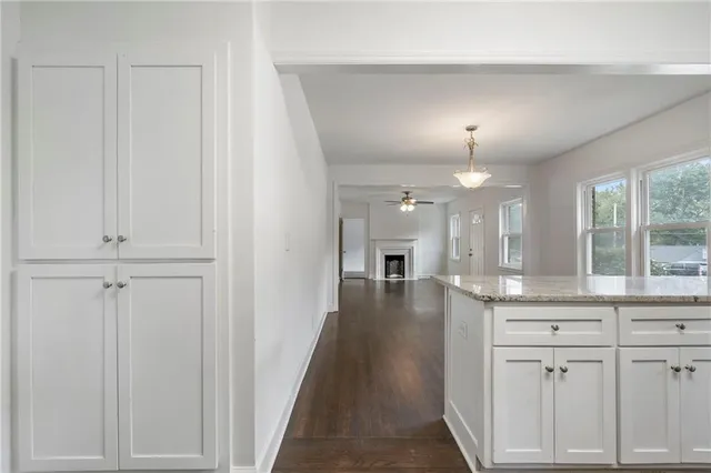 a view of a hallway with granite countertop a couch a chandelier a mirror and a window