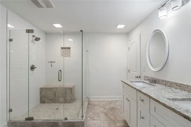 a bathroom with a granite countertop sink a mirror and a shower