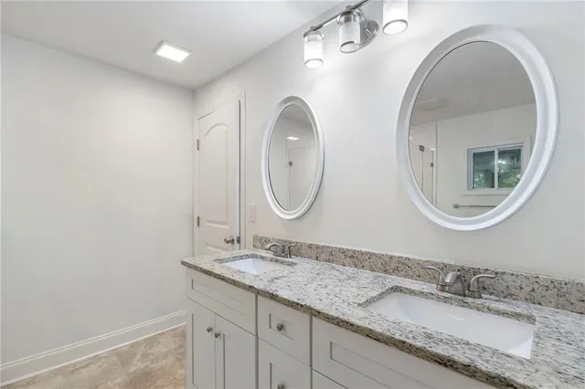 a bathroom with a granite countertop double vanity and a mirror