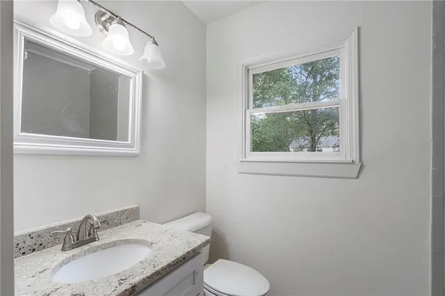 a bathroom with a granite countertop toilet sink and mirror