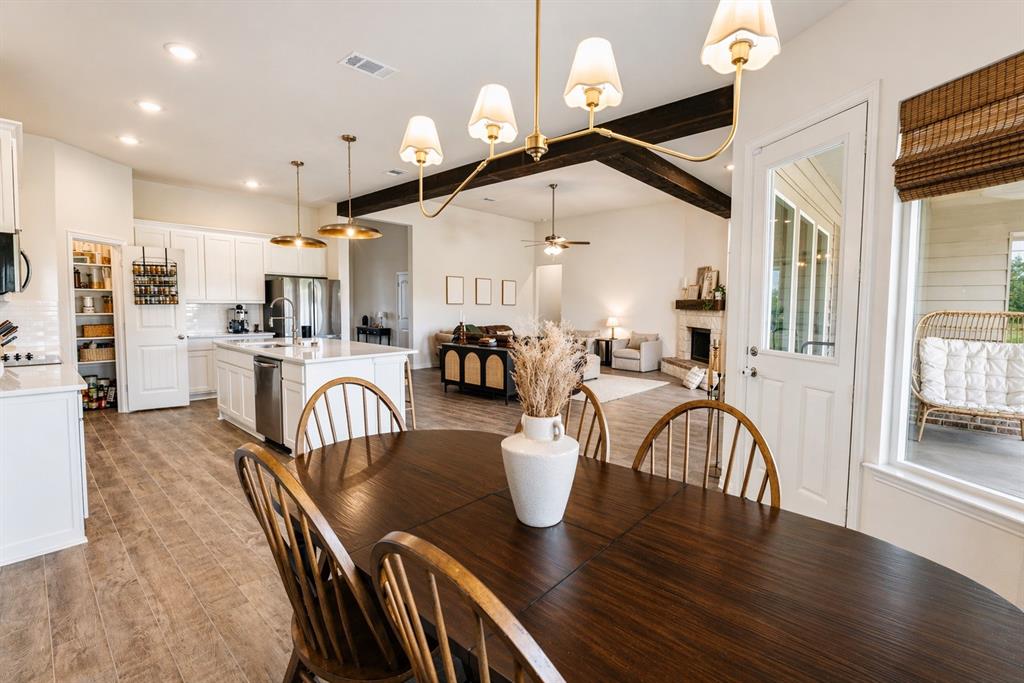 1530 County Road 200 Valley View, TX 76272 - Photo 5 of 34 Open-concept dining area featuring wood-finish flooring, a contemporary chandelier, and a white kitchen with a central island