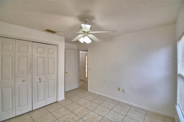 an empty room with windows and fan