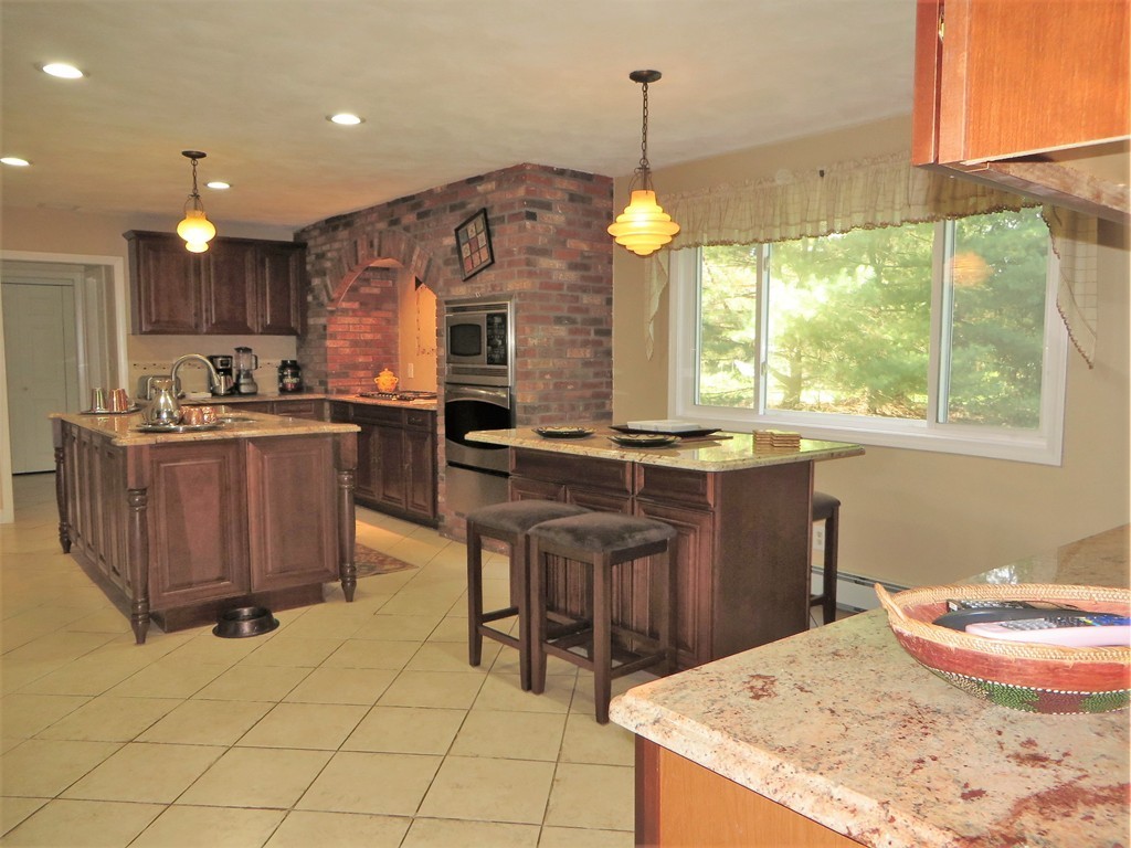 24 Raynor Road Sudbury, MA 01776 - Photo 5 of 30 a kitchen with kitchen island granite countertop a stove a sink a counter top space and living room view