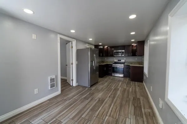 an empty room with wooden floor mirror and windows