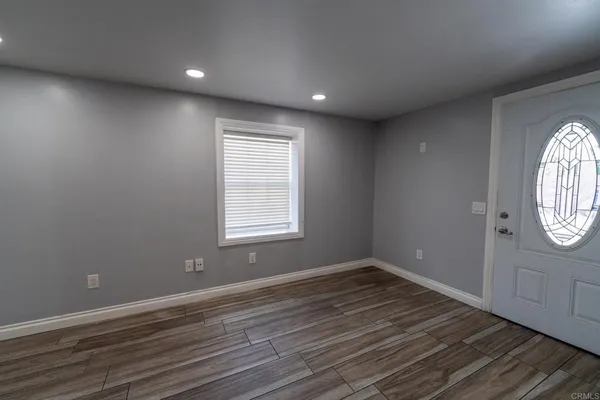 a view of an empty room with wooden floor and a window