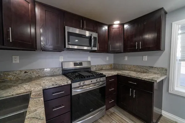 a kitchen with granite countertop a refrigerator and a stove top oven