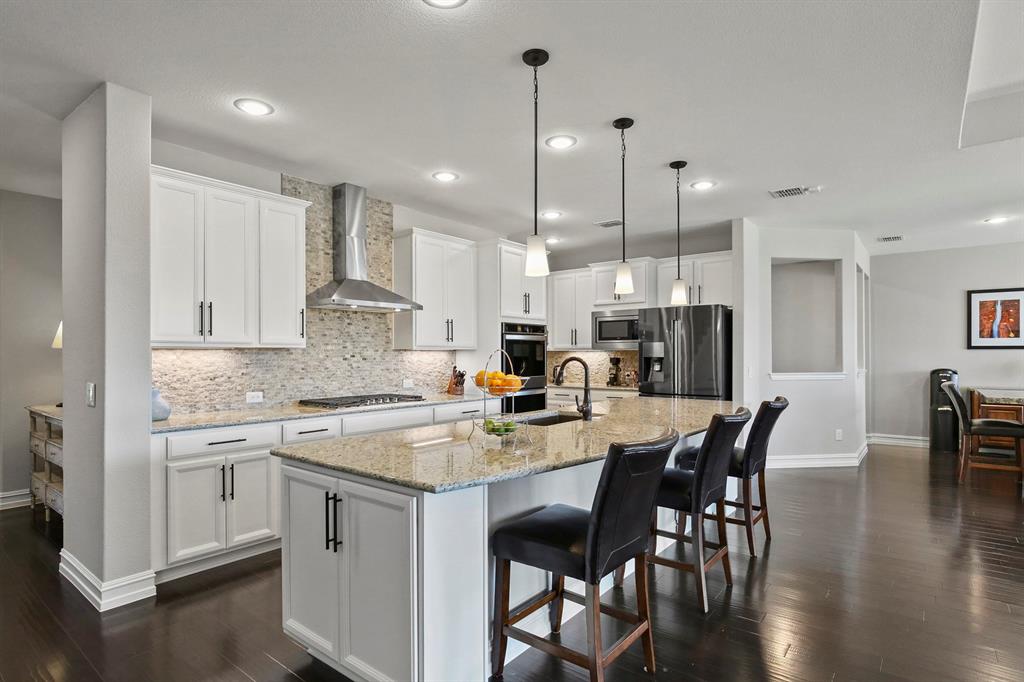 a kitchen with stainless steel appliances granite countertop a sink a stove a dining table chairs and view living room