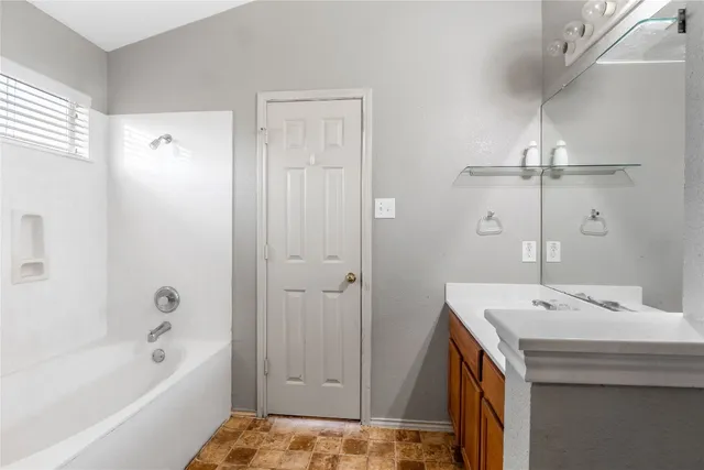 a bathroom with a tub sink and mirror