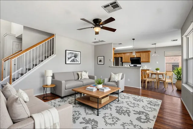 a living room with furniture kitchen view and a wooden floor