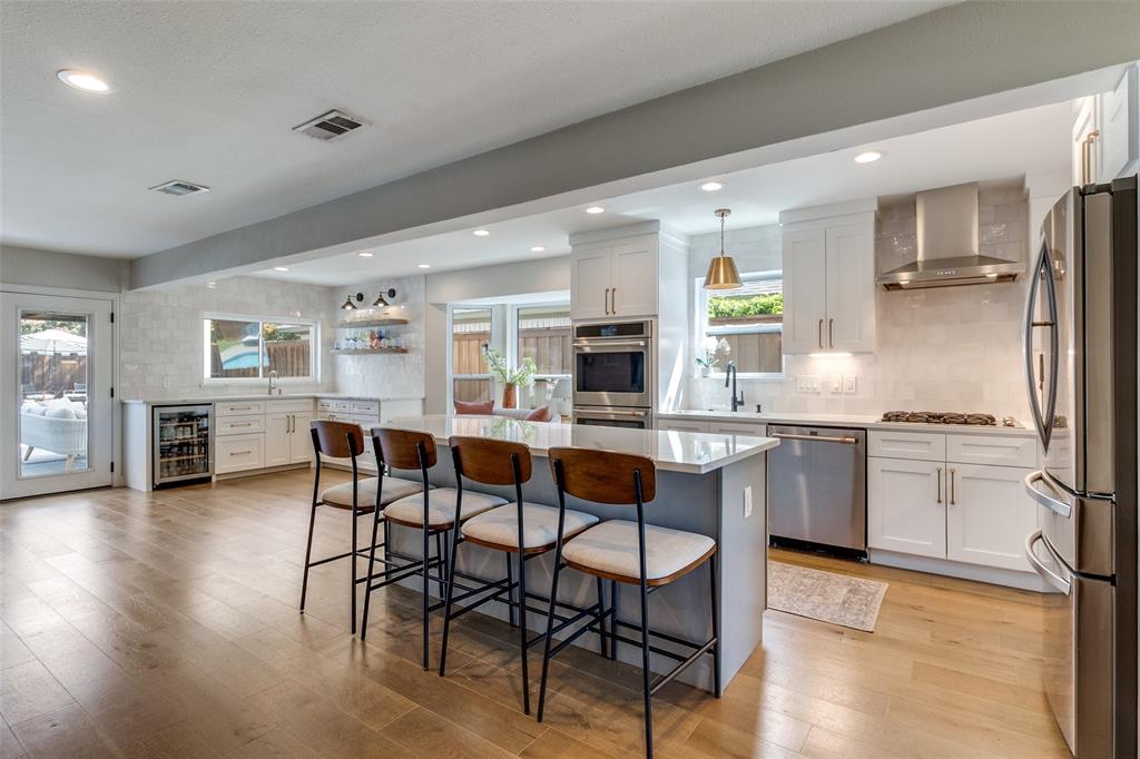 9243 Moss Farm Lane Dallas, TX 75243 - Photo 11 of 37 a kitchen with stainless steel appliances kitchen island granite countertop a table chairs sink and cabinets