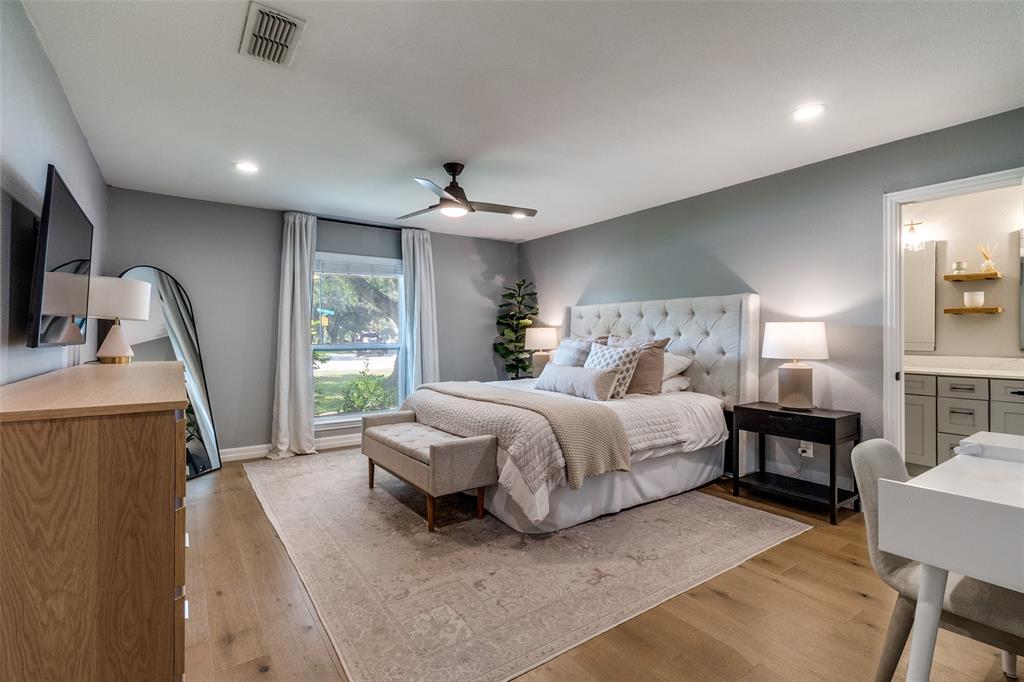 9243 Moss Farm Lane Dallas, TX 75243 - Photo 17 of 37 a spacious bedroom with a bed a table and large mirror