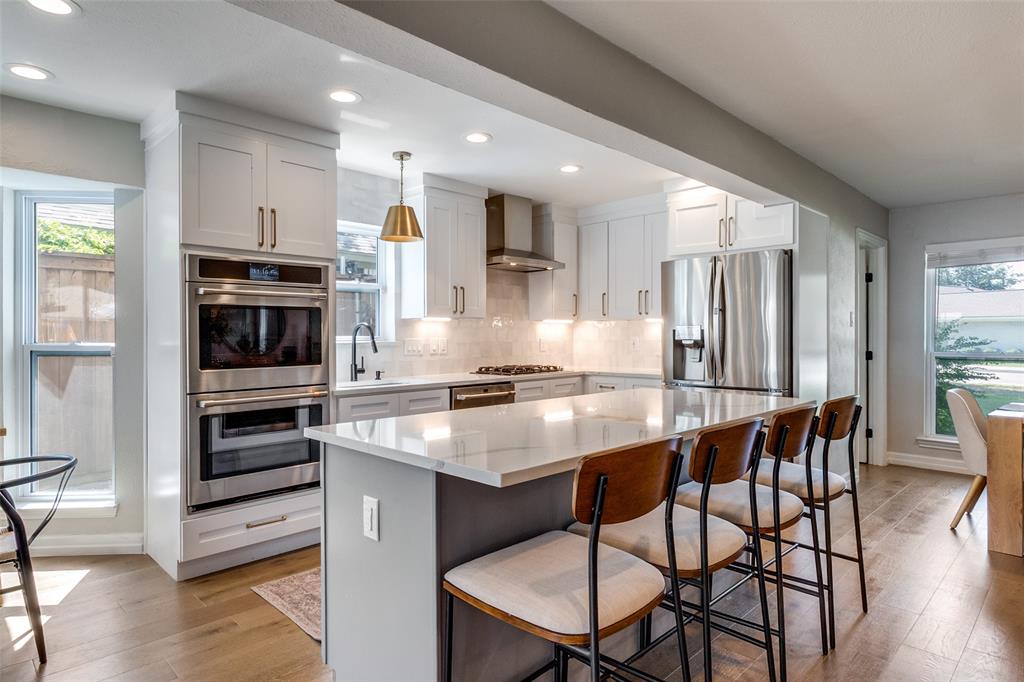 9243 Moss Farm Lane Dallas, TX 75243 - Photo 9 of 37 a kitchen with stainless steel appliances granite countertop a stove a refrigerator and a dining table with wooden floor