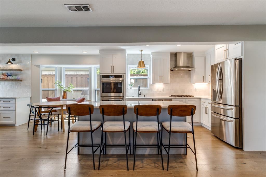 9243 Moss Farm Lane Dallas, TX 75243 - Photo 10 of 37 a kitchen with stainless steel appliances kitchen island granite countertop a table chairs and a refrigerator