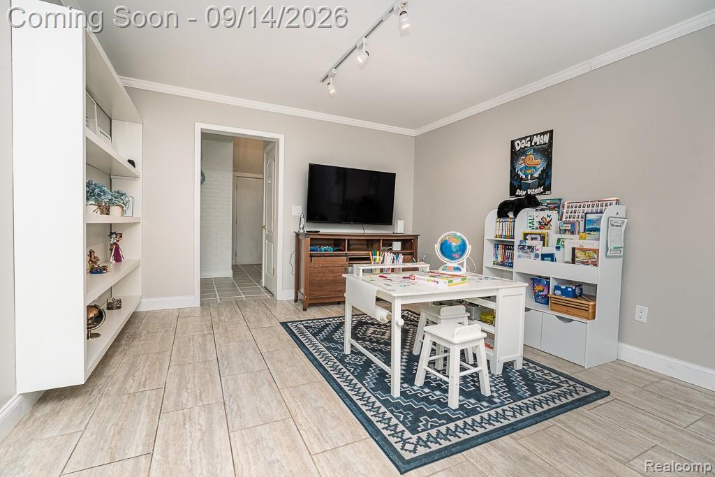 Light-toned plank flooring, white wall shelving, track lighting, and a doorway with tiled flooring