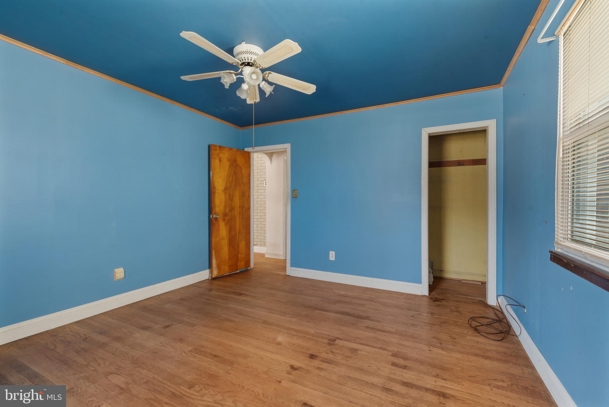 5016 Morello Road Baltimore, MD 21214 - Photo 7 of 16 an empty room with wooden floor chandelier fan and windows