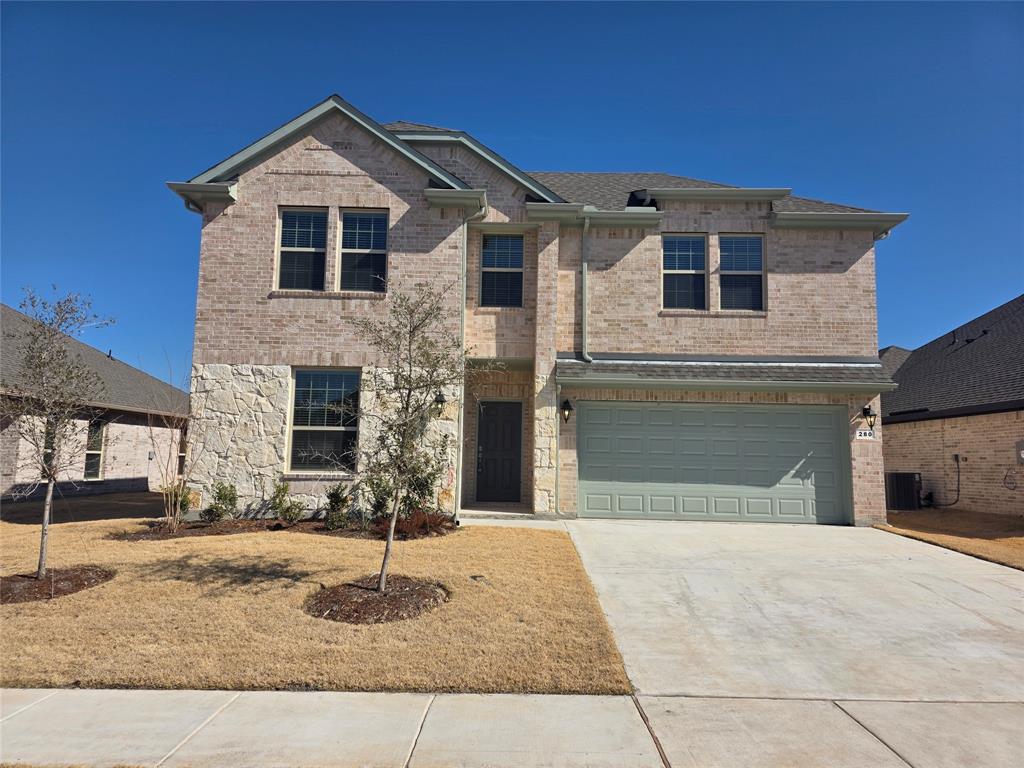 View of front facade featuring brick siding, an attached garage, driveway, and stone siding