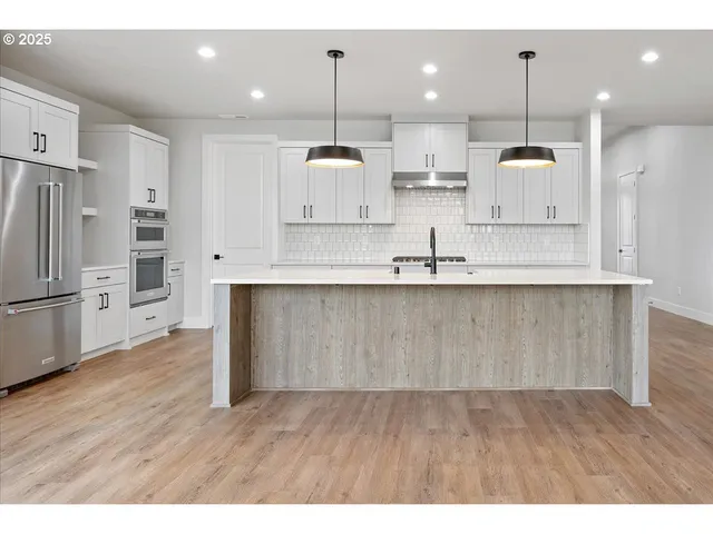 a kitchen with kitchen island white cabinets and refrigerator