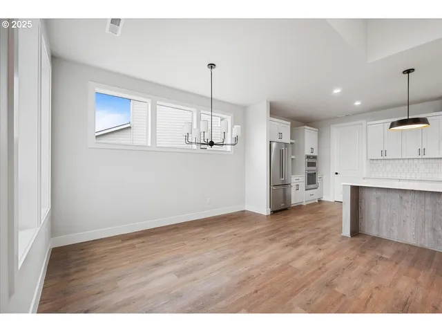 a view of a kitchen with refrigerator and wooden floor
