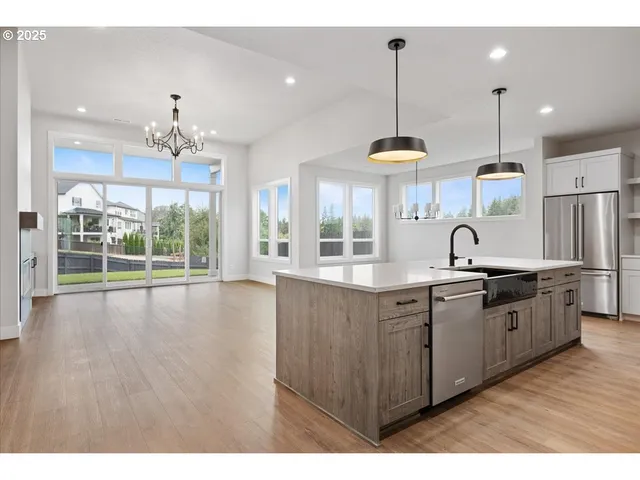 a large kitchen with stainless steel appliances a large counter tops a stove a sink dishwasher a kitchen island with wooden cabinets and floor