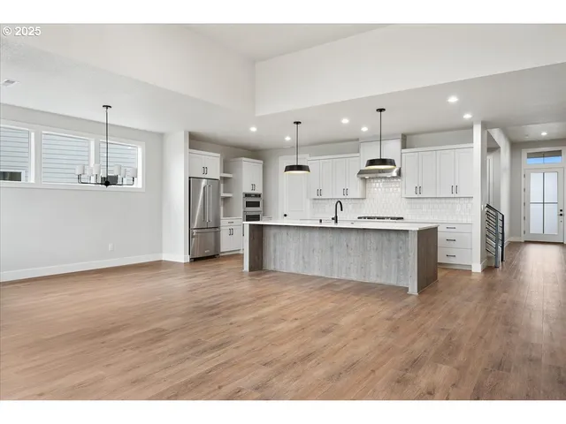 a large kitchen with stainless steel appliances kitchen island a large counter top and a wooden floors