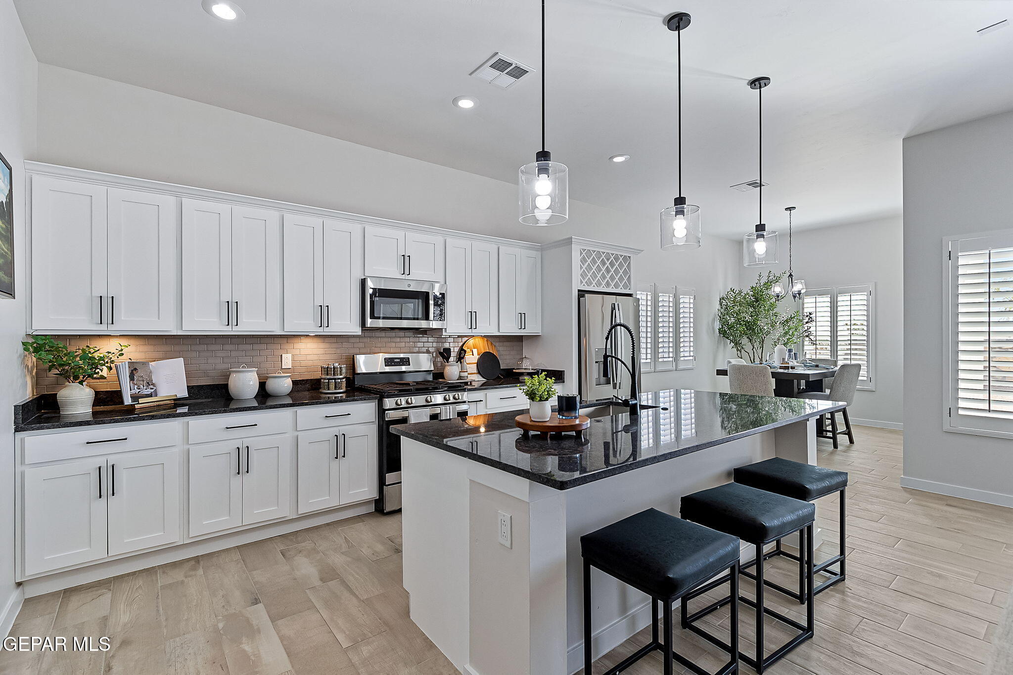 3849 Object Place El Paso, TX 79938 - Photo 4 of 18 a kitchen with granite countertop a stove a sink a refrigerator a stove a dining table and chairs
