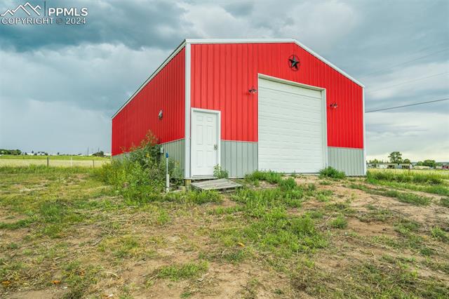 12550 Smith Road Peyton, CO 80831 - Photo 6 of 35 View of outdoor structure featuring a garage and a rural view