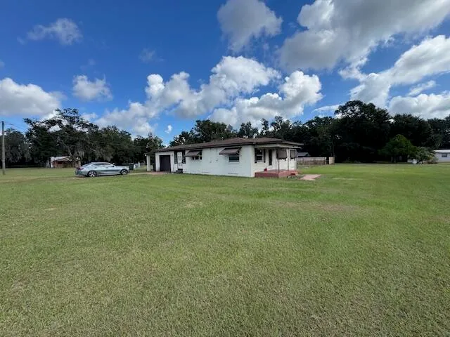 a view of a house with a big yard and large trees